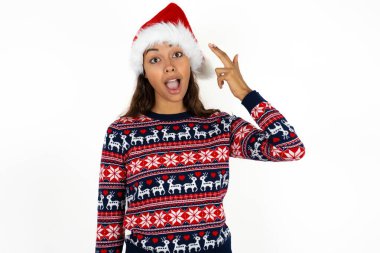 Güzel İspanyol kadın örgü süveter ve Noel Baba şapkası takıp beyaz arka planda şapkalar takıyor. Çekimler sırasında parmaklarıyla intihar jesti yapıyor. Komik manken parmak tabancası yapar.