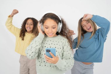 Akıllı telefon ekranına odaklanmış üç güzel, çok ırklı kız çocuğu kendini iyi hissediyor. İnsanlar, teknoloji, yaşam tarzı