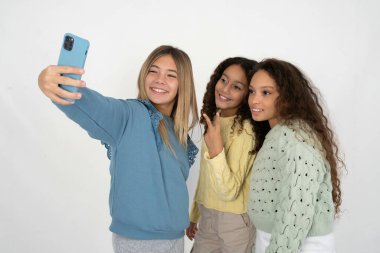 Üç güzel, çok kültürlü kız çocuğu gülümsüyor ve kendi sosyal medyasında paylaşmaya hazırlanıyor..