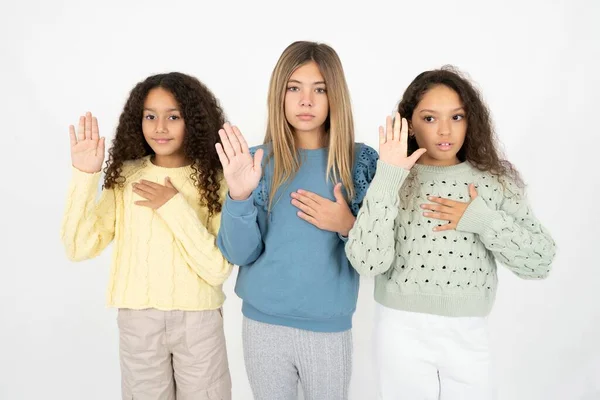 Tre Unge Smukke Multiracial Kid Piger Sværger Med Hånd Brystet - Stock-foto