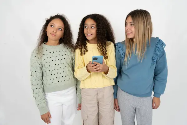 手の携帯電話で保持し 夢のような外観を見ている3人の若い美しい多人種間の子供の少女 — ストック写真
