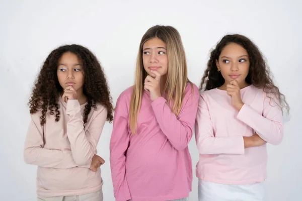 三个年轻貌美的多种族小女孩托着下巴 沉思地把目光移开 形成了一个伟大的计划 — 图库照片