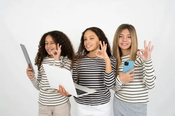三个年轻貌美的多种族小女孩用笔记本电脑展示了Ok Sign Winkin — 图库照片