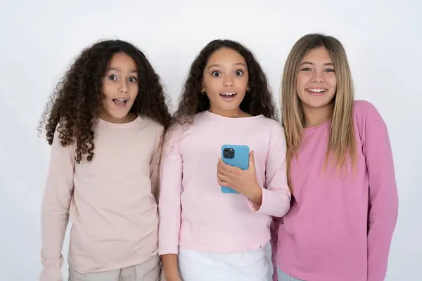 Three Young Beautiful Multiracial Kid Girls Holds Mobile Phone Hands Stock Photo