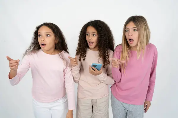 Stunned Three Young Beautiful Multiracial Kid Girls Points Sideways Right Royalty Free Stock Photos