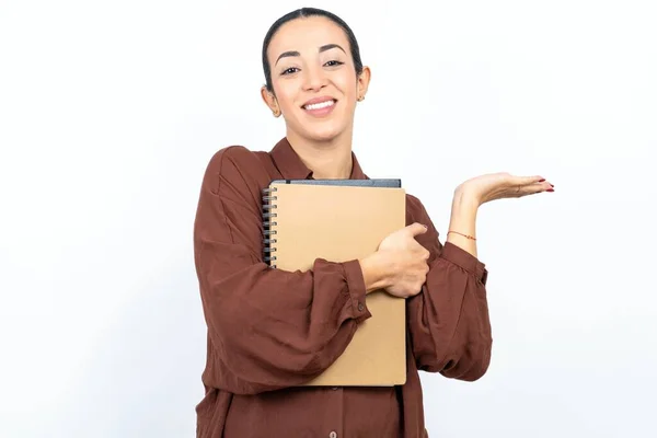 美丽的女性阿拉伯学生拿着笔记本 带着纸 笑容满面 手指手画脚地看着相机 — 图库照片