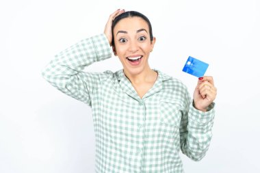 Yeşil ekose pijama giyen güzel bir kadın beyaz arka plan üzerinde banka kartı tutan bir el.