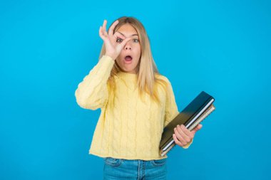 Sarı kazak giyen güzel kız şaşırmış yüz ifadesiyle şok olmuş, parmaklarından bakan gözler. İnançsız ifade.