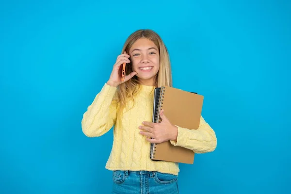 笑美丽的小女孩穿着黄色毛衣通过手机聊天 享受愉快愉快的交谈 通信概念 — 图库照片