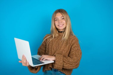 Kahverengi örgü süveter giyen güzel kız modern bir alet tutuyor.