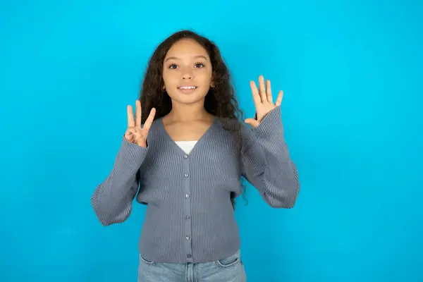 漂亮的小女孩穿着休闲装 穿着蓝色背景的衣服 手指指向八号 面带微笑 自信而快乐 — 图库照片