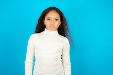 Hoşnut olmayan güzel kız beyaz balıkçı yaka giyen mavi arkaplan kaşlı surat mutsuz hissediyor bazı problemleri var. Olumsuz duygular ve duygular konsepti