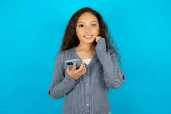 Радостная Красивая Девочка Повседневной Куртке Синем Фоне Позы Мобильным Телефоном — стоковое фото