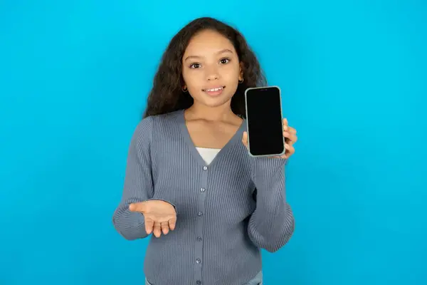 モバイルで青い背景にカジュアルなジャケットを着ている美しい少女 スマートフォンを発表 広告コンセプト — ストック写真