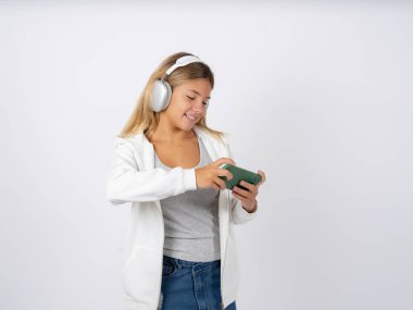 Kulaklık takan, beyaz ceketli genç bir kız. Stüdyonun arka planında. Hücrede el ele tutuşup oyun oynuyor ya da sohbet ediyor. 