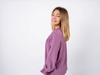 Satisfied pretty beautiful teenager girl wearing purple T-shirt over white studio background beaming smile look camera clipart