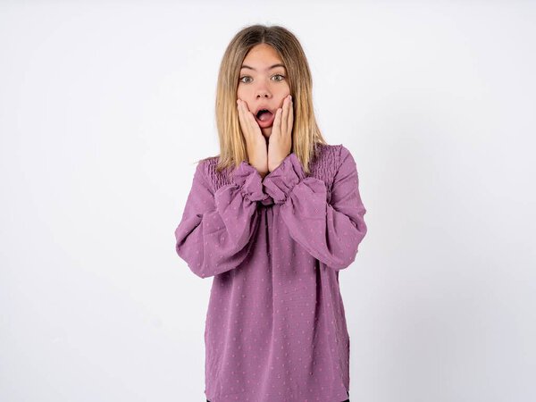 Scared terrified beautiful teenager girl wearing purple T-shirt over white studio background shocked with prices at shop, People and human emotions concept