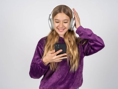 Mor kazak giyen mutlu genç kız akıllı telefon ekranında odaklanırken kendini iyi hissediyor. İnsanlar, teknoloji, yaşam tarzı