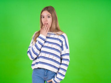 Yeşil stüdyo arka planında çizgili süveter giyen güzel bir genç kız ağzını kapatıyor ve kameraya hayretle bakıyor. Beklenmedik söylentilere inanamıyor..