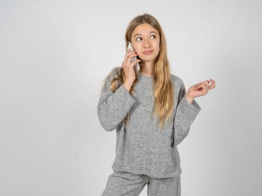 Gri eşofman giyen güzel genç kız cep telefonuyla konuşuyor. Boş vakitlerini evde arkadaşlarıyla görüşerek geçiriyor..