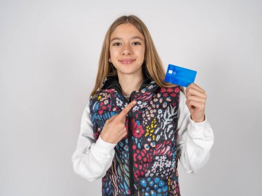 Renkli yelek giyen güzel bir kızın fotoğrafı. Parmakla kredi kartıyla alışveriş yapıyor.