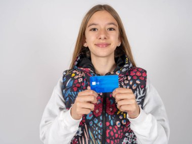 Renkli yelek giyen güzel bir kızın fotoğrafı. Gülümsemesi olumlu. Kredi kartı geliri maaşı var. 