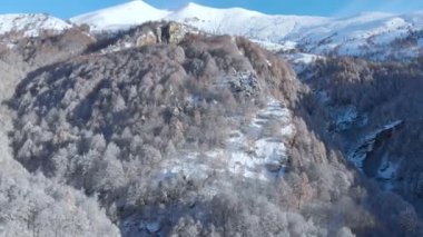 Karla kaplı dağların havadan görünüşü manzaralı vadi cennet gibi dağ köyü ve Noel zamanı dağlık ağaçlık arazi, kış mevsimi beyaz manzara. İtalyan Alpleri.