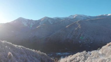 Aerial view of snowcapped mountains scenic valley idyllic mountain village and alpine woodland in winter season white landscape. The italian Alps.