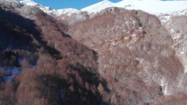 Aerial view of snowcapped mountains scenic valley idyllic mountain village and alpine woodland in winter season white landscape. The italian Alps.