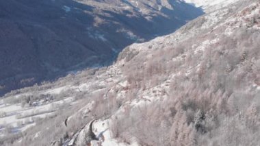 Aerial view of snowcapped mountains scenic valley idyllic mountain village and alpine woodland in winter season white landscape. The italian Alps.