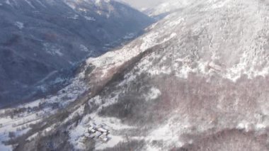 Aerial view of snowcapped mountains scenic valley idyllic mountain village and alpine woodland in winter season white landscape. The italian Alps.