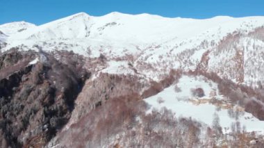 Aerial view of snowcapped mountains scenic valley idyllic mountain village and alpine woodland in winter season white landscape. The italian Alps.