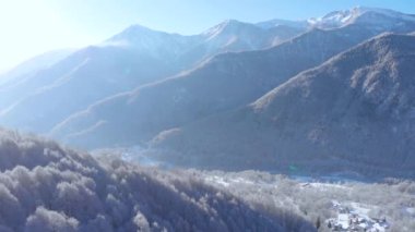 Aerial view of snowcapped mountains scenic valley idyllic mountain village and alpine woodland in winter season white landscape. The italian Alps.