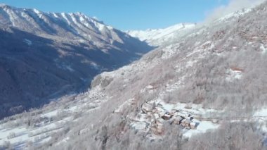Aerial view of snowcapped mountains scenic valley idyllic mountain village and alpine woodland in winter season white landscape. The italian Alps.