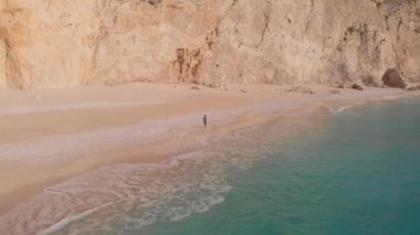 Yavaş çekim: Yunanistan 'da güzel boş bir plajda yürüyen ve dinlenen kadın görüntüsü. İyon adası Port Katsiki, Lefkada 'daki dramatik sahil manzaralı kayalık uçurumlar.