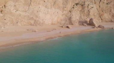 Yavaş çekim: Yunanistan 'da güzel boş bir plajda yürüyen ve dinlenen kadın görüntüsü. İyon adası Port Katsiki, Lefkada 'daki dramatik sahil manzaralı kayalık uçurumlar.