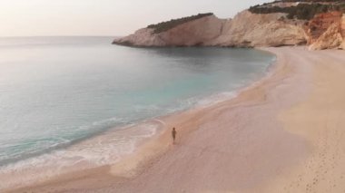 Yavaş çekim: Yunanistan 'da güzel boş bir plajda yürüyen ve dinlenen kadın görüntüsü. İyon adası Port Katsiki, Lefkada 'daki dramatik sahil manzaralı kayalık uçurumlar.