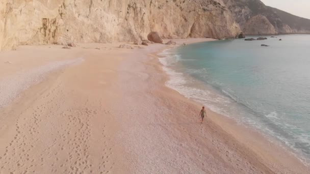 ゆっくりとした動き ギリシャの美しい空のビーチで歩いてリラックスする女性の空中ビュー イオニア島の劇的な海岸線の風光明媚な湾岩の崖 ポートカチキ レフナ — ストック動画