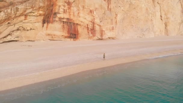 ゆっくりとした動き ギリシャの美しい空のビーチで歩いてリラックスする女性の空中ビュー イオニア島の劇的な海岸線の風光明媚な湾岩の崖 ポートカチキ レフナ ストック映像