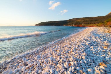 Günbatımı manzaralı güzel sahil ve Yunan muhteşem sahil şeridinde su koyları. Turkuaz mavi su benzersiz beyaz çakıl taşları, Yunanistan yazın en iyi seyahat noktası Mani yarımadası Moreloponnese