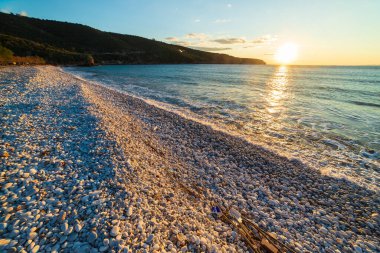 Günbatımı manzaralı güzel sahil ve Yunan muhteşem sahil şeridinde su koyları. Turkuaz mavi su benzersiz beyaz çakıl taşları, Yunanistan yazın en iyi seyahat noktası Mani yarımadası Moreloponnese