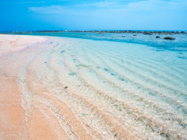 Andaman Adaları 'ndaki tropikal plajda kristal berraklığında süzülen su. Turkuaz su, arka planda yeşil orman olan el değmemiş kumlu bir sahilde nazikçe süzülüyor.