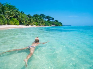 Tenha bir sahil cennetinin el değmemiş mavi sularında zahmetsizce süzülen bir kadının sakin görüntüsü. Andaman Adaları, Hindistan