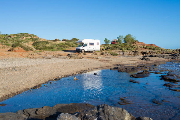 Serene seaside rv camping experience, Motorhome parked by a tranquil coastal inlet under a clear blue sky. Peloponnese, Greece.