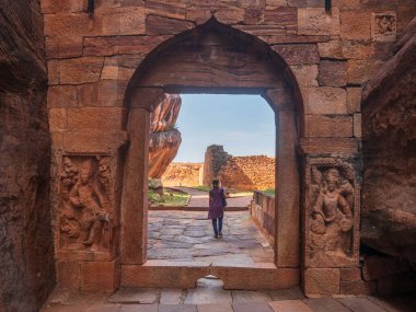 Badami 'deki eski tapınak alanını keşfeden bir kadın. Hindistan, Karnataka 'da harabelerin arasında yürüyen bir turist.