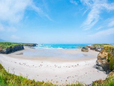 Katedrais sahili Galiçya 'da sular çekildiğinde İspanya kumtaşı gelgit havuzlarını gökyüzü kayalıklarını yansıtan geniş kayalıklar parlak ışık altında barışçıl doğal merak altında uzanır.