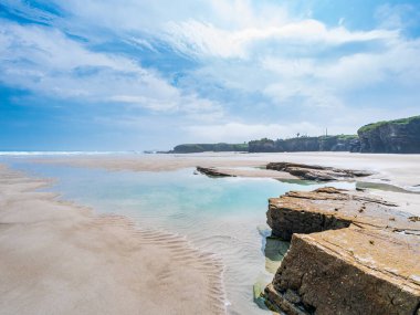 Katedrais sahili Galiçya 'da sular çekildiğinde İspanya kumtaşı gelgit havuzlarını gökyüzü kayalıklarını yansıtan geniş kayalıklar parlak ışık altında barışçıl doğal merak altında uzanır.