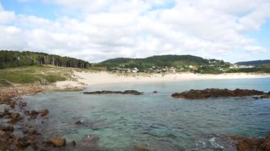 Playa de Doninos Galiçya 'da açık bir gün. İspanya turkuvaz suyu. Kayalık kıyı ormanı.