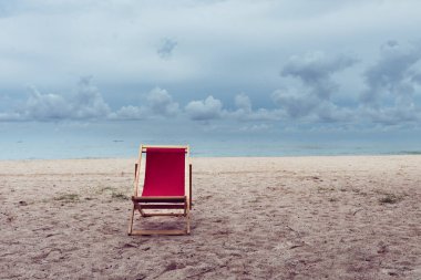 Sahilde boş kırmızı plaj koltuğu, plaj tatili ve rahatlatıcı konsept..