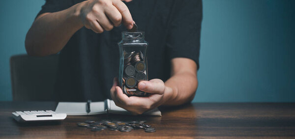 Young man putting coin in to jar, saving, charity, family finance plan concept, fundraising, superannuation, investment, financial crisis concept